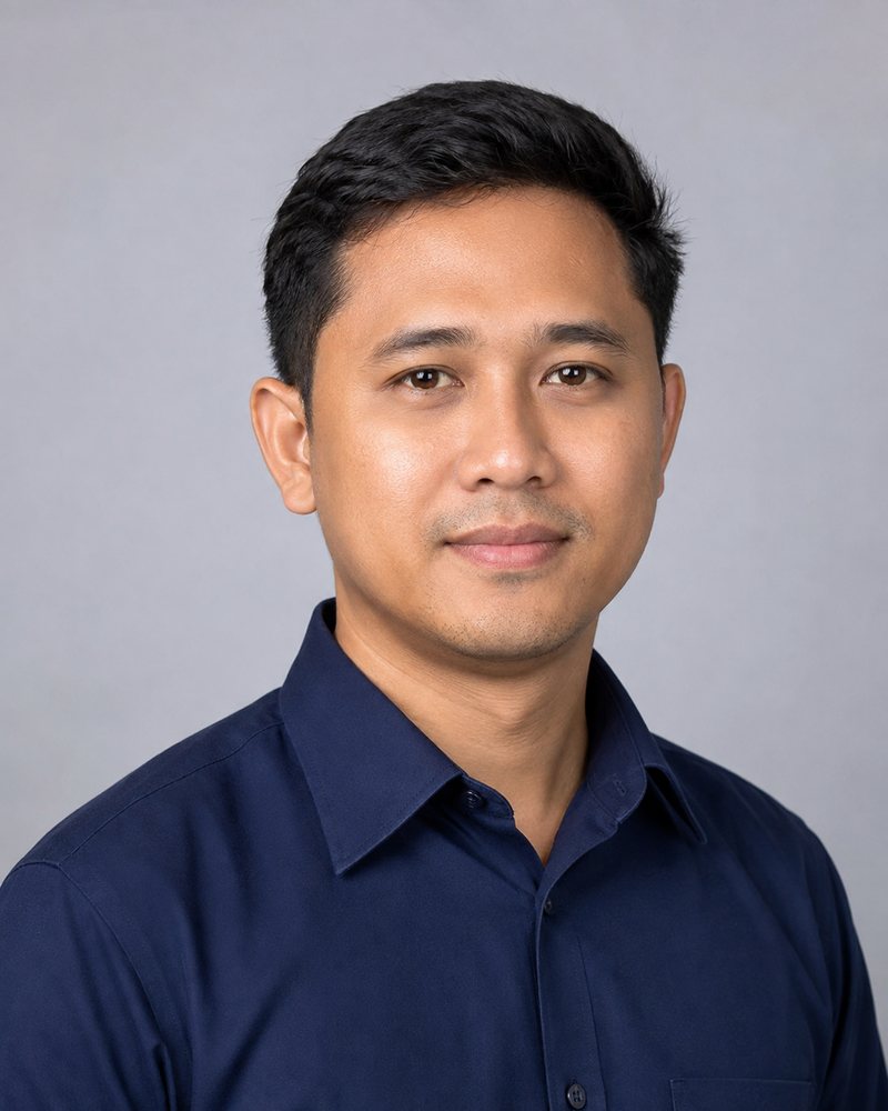 Potret studio lelaki berusia tiga puluhan berbaju kerja biru gelap dengan latar kelabu neutral